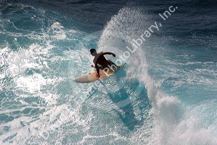 Surfing on waves in the pacific ocean off the island of Maui, Hawaii.