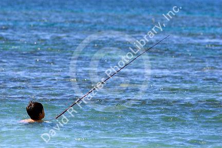 Young boy fishing in the pacific ocean off the island of Maui, Hawaii.