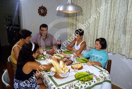 Brazilian family eating dinner at the table in their home, Brazil.