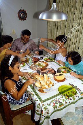 Brazilian family eating dinner at the table in their home, Brazil.