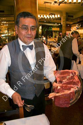 Waiter displays plate of raw beef at Estancia, a famous restaurant in Argentina.