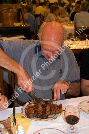 Customer eating a huge t-bonesteak at Estancia a famous restaurant in Buenos Aires,  Argentina.