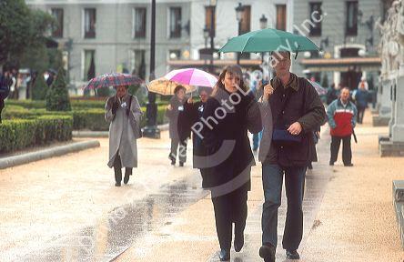 Pedestrians walking in the rain using umbrellas in Madrid, Spain.