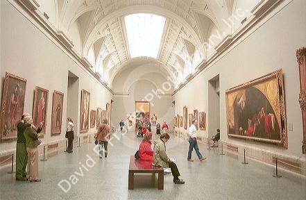 Interior of the Prado art museum showing paintings and visitors in Madrid, Spain.