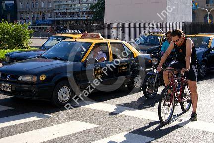 Bicyclists and taxis wait in traffic. Buenos Aires, Argentina.