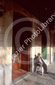 Elderly man sitting at entrance to bar in Majorca, Spain.