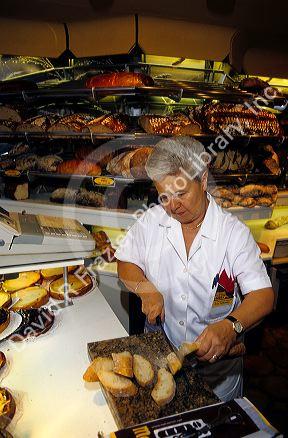 A German woman cuts fresh bread at a bakery in Cologne, Germany.