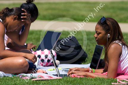 African american female students study using laptop computers on the lawn of Albion College in Michigan.