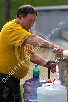 A man filling water jugs from a public water fountain in Hot Springs, Arkansas.