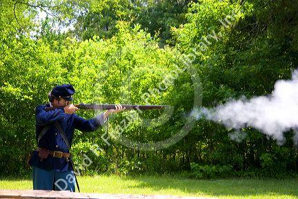 Civil war soldier reenactor and park ranger fires a musket at Shiloh National Park battlefield, Tennessee.