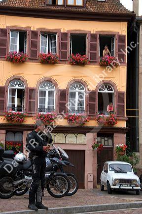 A man wearing motorcycle riding gear and talking on a cell phone in front of apartments in the village of Ribeauville, Eastern France.