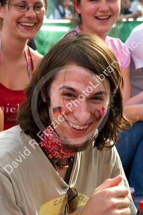 German soccer fan outdoors at the Munich airport watching a 2006 World Cup match on big screen televisions, Germany.