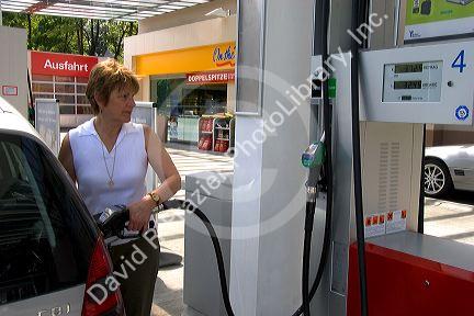 Woman fueling a car at a gas station in Friesing, Germany. MR