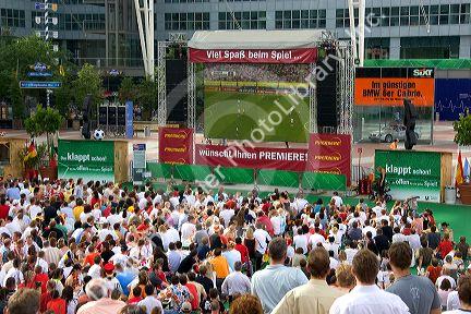 A crowd of soccer fans gather outdoors at the Munich airport watch a 2006 World Cup match on big screen televisions, Germany.