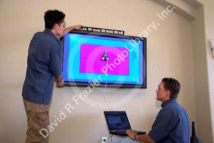 Technicians install and calibrates flat screen plasma television.