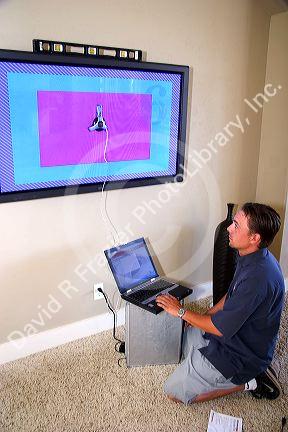 Technician installs and calibrates flat screen plasma television.