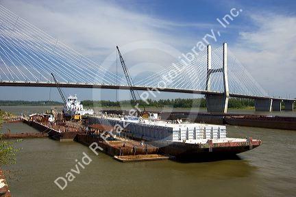 A tugboat and barge on the Mississippi River cross under a modern suspension bridge at Cape Girardeau, Missouri.