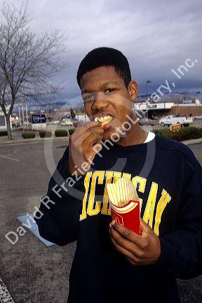 African american teen eating french fries.