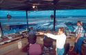 Four men working in an air traffic control tower. One man is talking on the phone pointing.