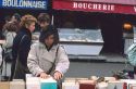 Woman looking through books at an outdoor market in Paris, France.