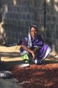 Woman drying chili peppers in India.