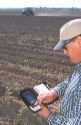 Farmer uses a palm pilot, (PDA) to record chemical use in the field.