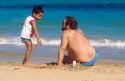 Father and son play in the sand at the beach in Pueto Rico.
