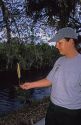 A female forest service emplyee in the Florida everglades uses a sling psychrometer for humidity testing in the Big Cypress Swamp.