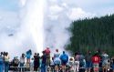 Tourists visiting Old Faithful Geyser during eruption in Yellowstone National Park, Wyoming.