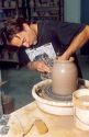 Potter using clay on a potters wheel.