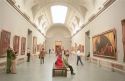 Interior of the Prado art museum showing paintings and visitors in Madrid, Spain.