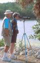 Senior citizens looking through spotting scopes at the J.H. Ding Darling National Wildlife Refuge on Sanibel Island, Florida.  Man is a volunteer at the refuge.