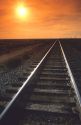 Railroad tracks converge at sunset.