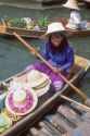 Woman selling hats from a boat at the Floating Market near Bangkok, Thailand.