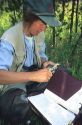 A female wildlife biologist measuring a frog in the field.