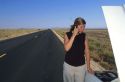 Stranded woman using a cell phone to call for help.