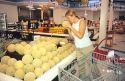 Woman shopping for cantilope in the produce section of a grocery store.