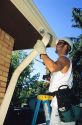 Worker putting on gutters and downspouts on a house.