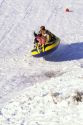 People sledding in the snow on an inflatable raft.