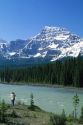 A woman takes a photograph of the Athabasca River and the Canadian Rockies in Jasper National Park, Canada.