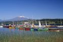 Boats docked at a marina with Villarica volcano in Villarica, Chile.