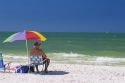 A senior citizen sitting under an umbrella at the beach in Clearwater, Florida.