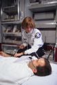 A female paramedic examines a patient inside an ambulance.