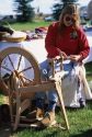 A woman using a spinng wheel to make wool into yarn.