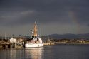 Rainbow over Monterey Bay, California with Coast Guard boat in port.