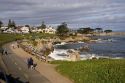 People jogging and walking along the rocky shore in Monterey, California.