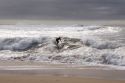 A man surfing the waves as they crash onto the beach north of Santa Cruz, Califronia.