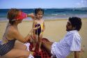 Hispanic family at the beach. Parents apply sunscreen to childs face.