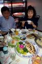 Chinese people eating a meal in a restaurant, Taiwan.  Woman has surprised look on her face.