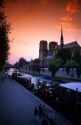 A view of the Notre Dame Cathedral at sunset in Paris, France with boats along the River Seine.